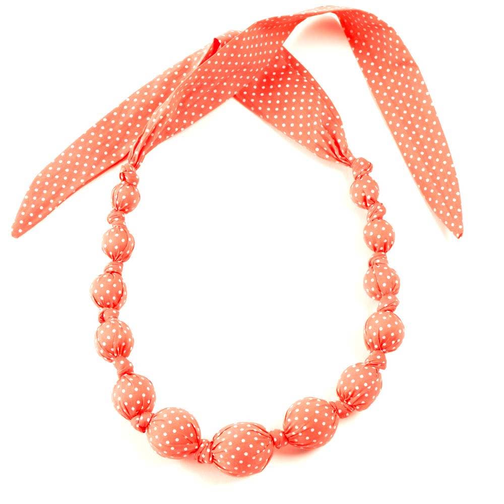Necklace with pink polka dot beads and matching headband on a white background