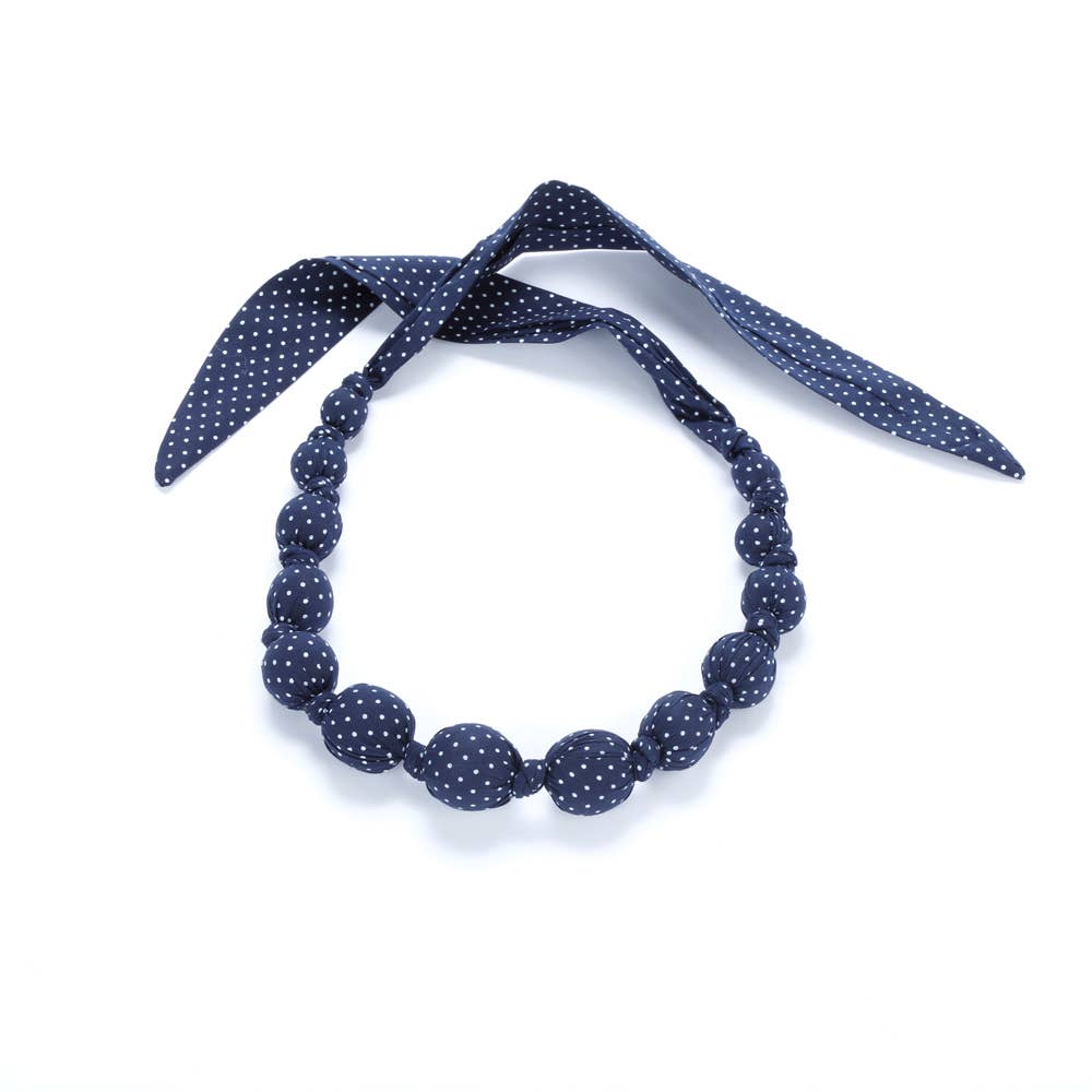 Navy blue polka dot headband with a matching necklace on a white background