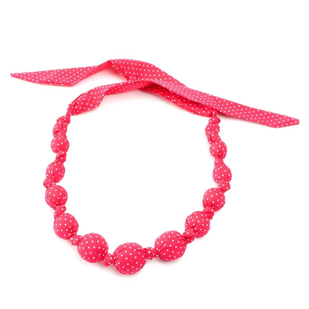 Necklace with pink polka dot beads and matching ribbon on a white background