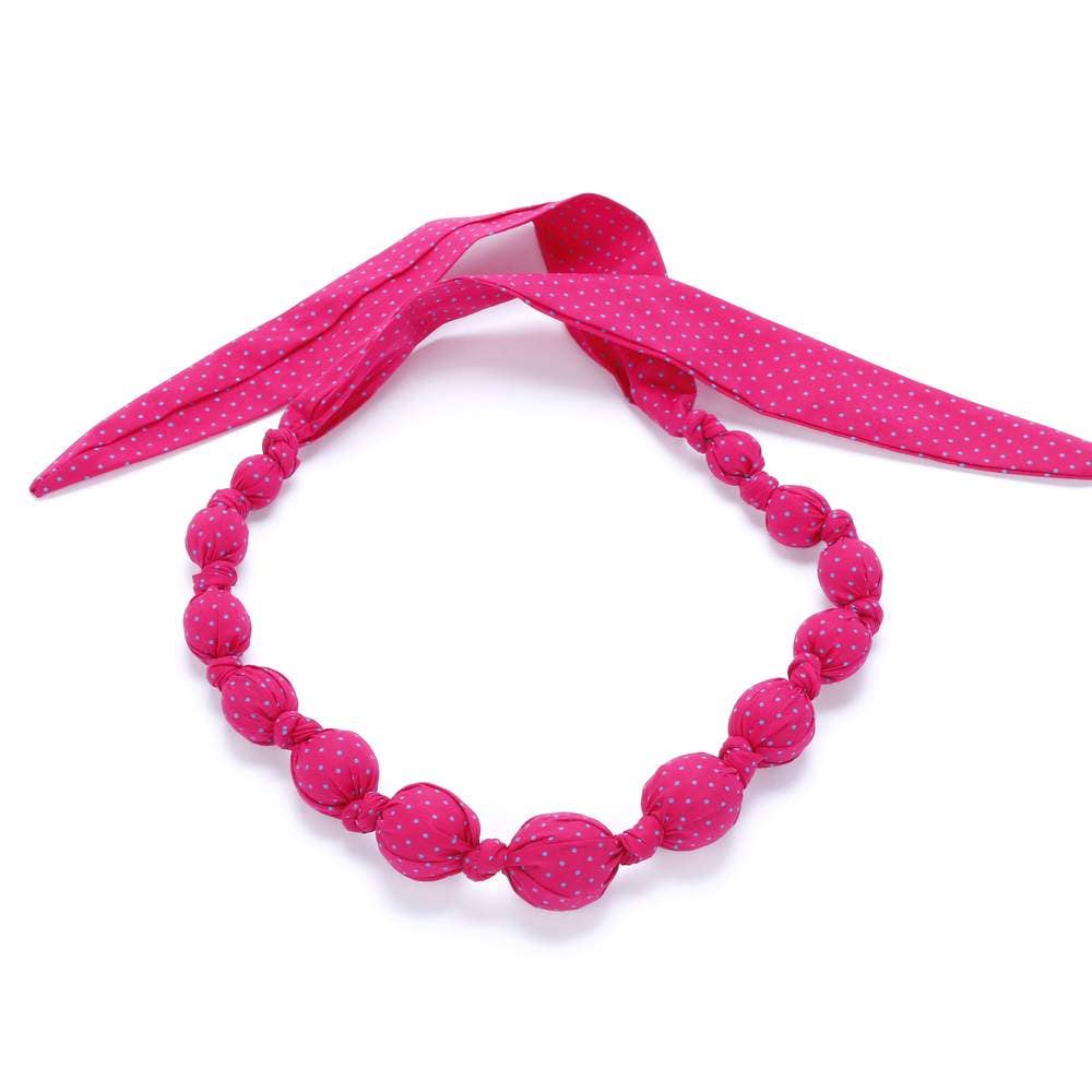 Pink polka dot necklace with matching headband on a white background